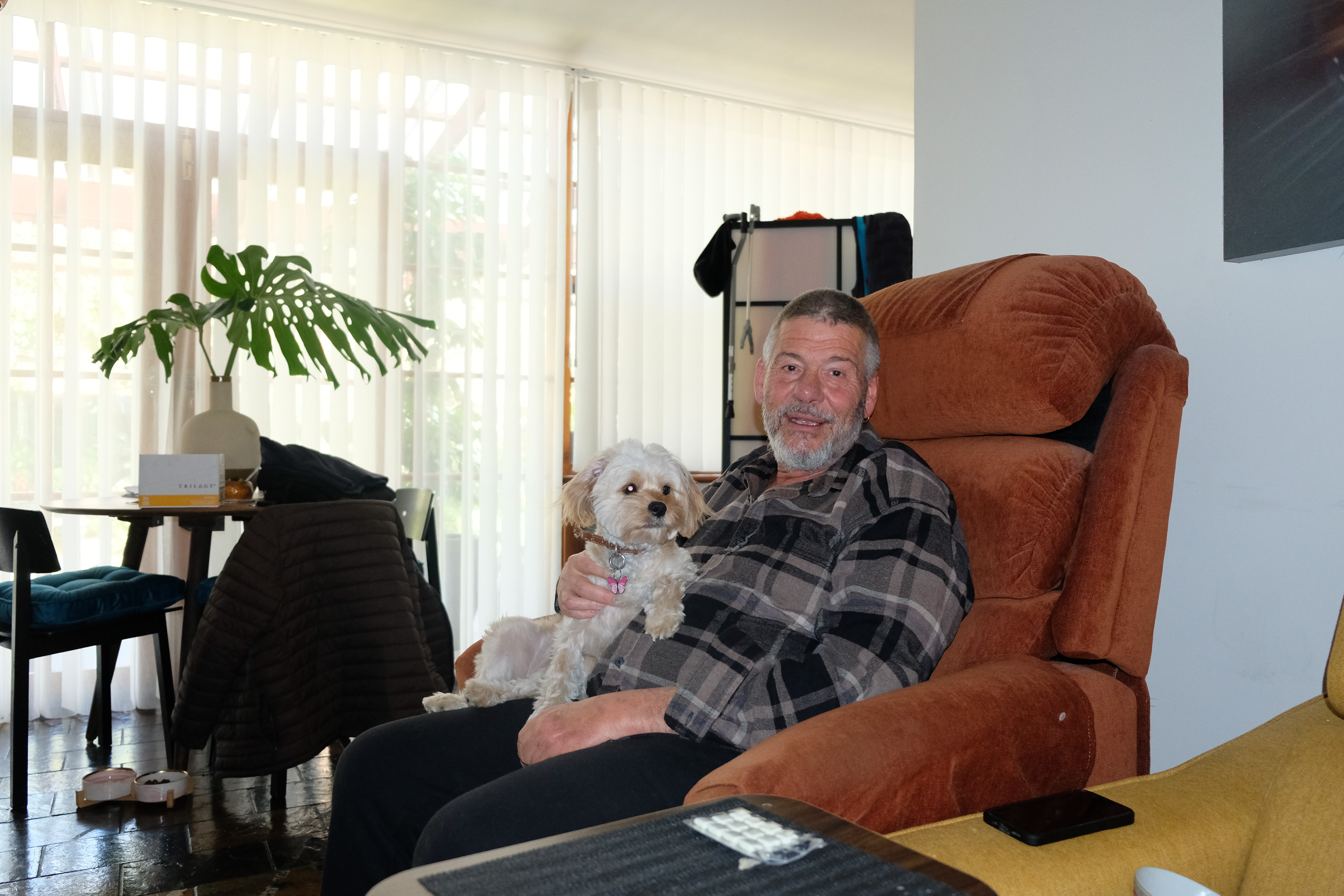Man sitting on couch, holding his dog.