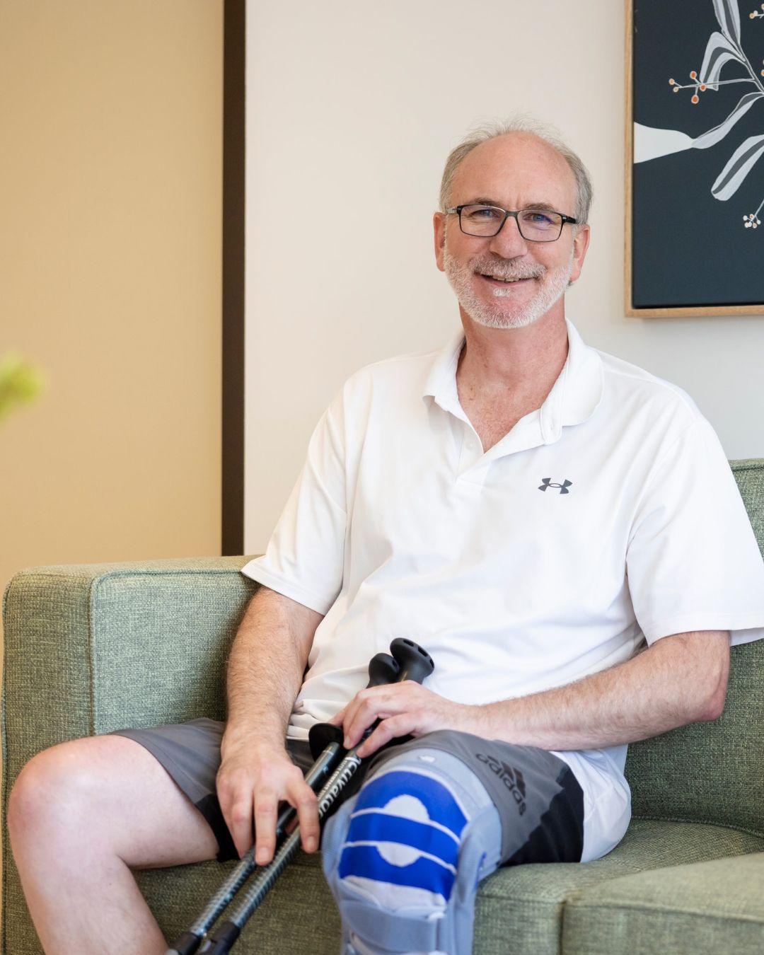 client with leg brace sitting on green couch