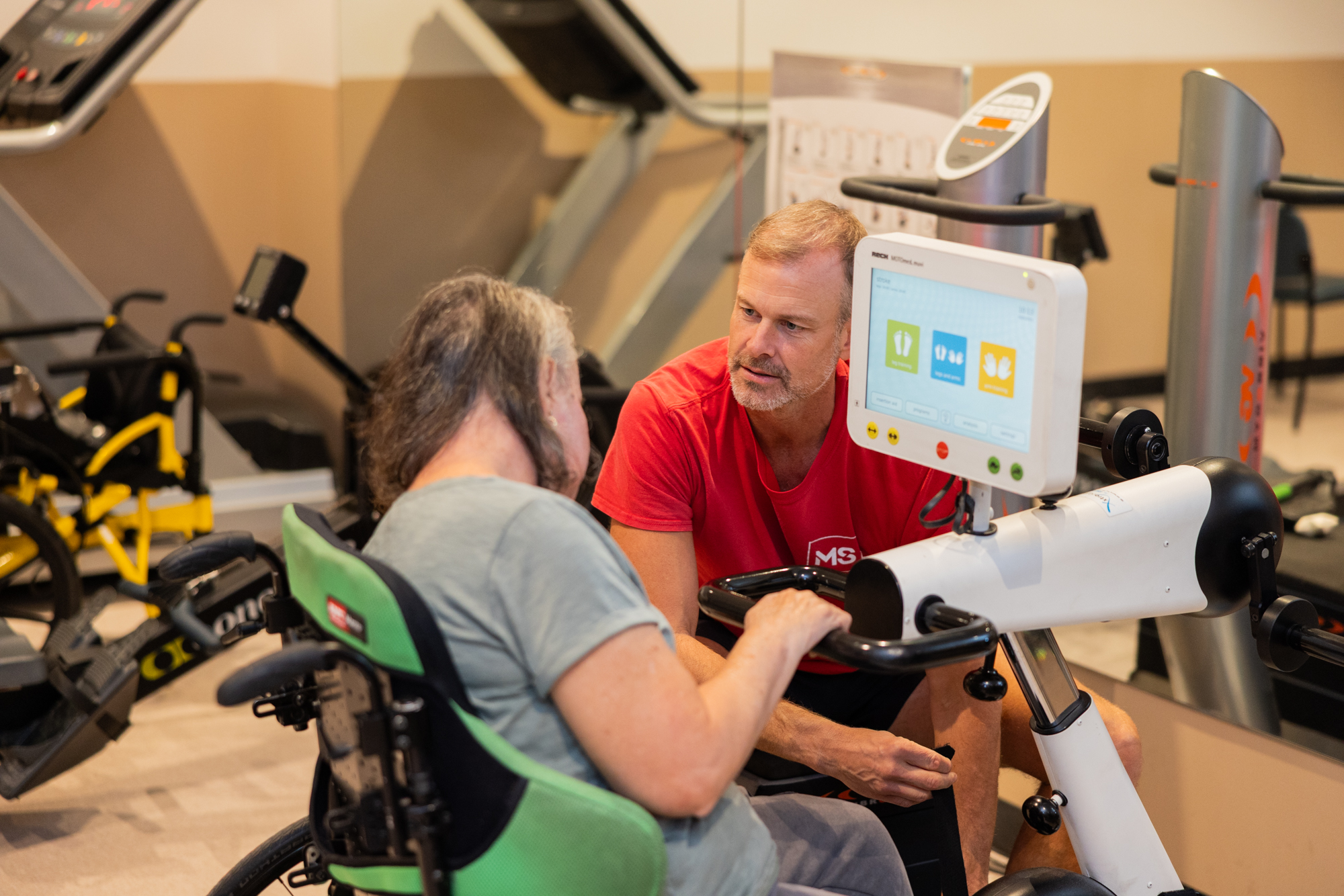 Exercise therapist talking to a client on an exercise bike.