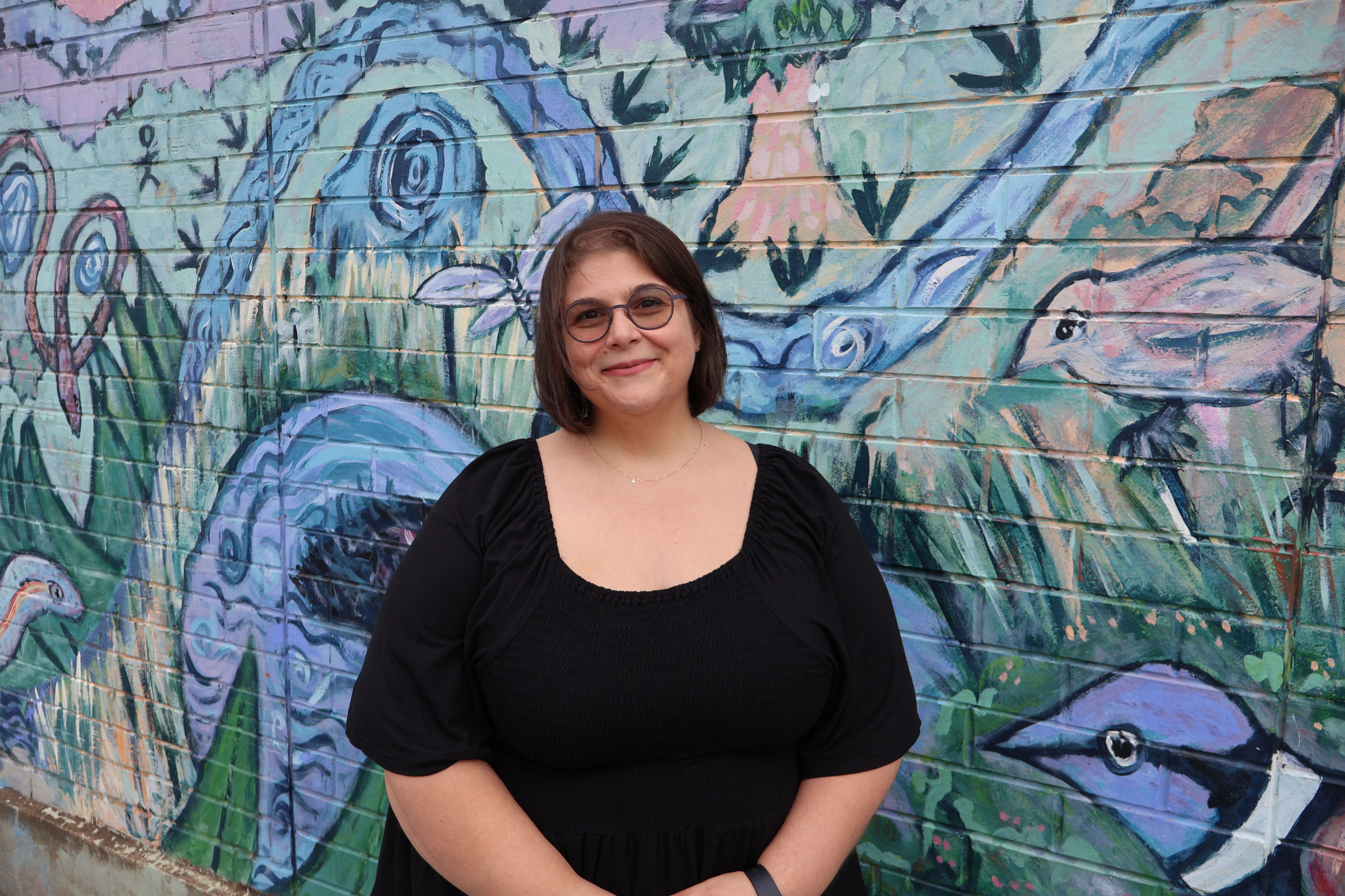 Woman standing next to a graffiti artwork wall.